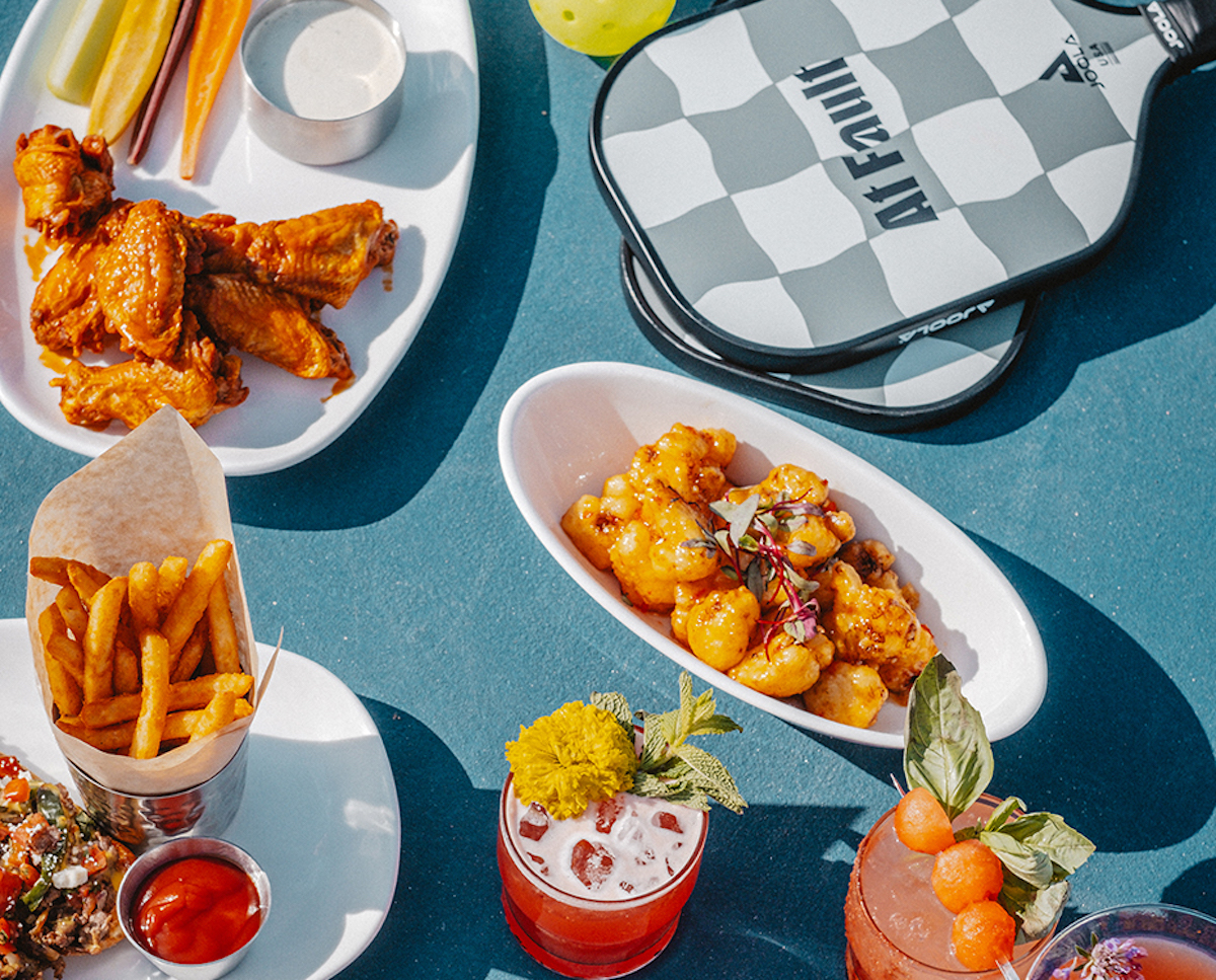 A spread of dishes and drinks with paddles on the court at At Fault. | Photo by At Fault